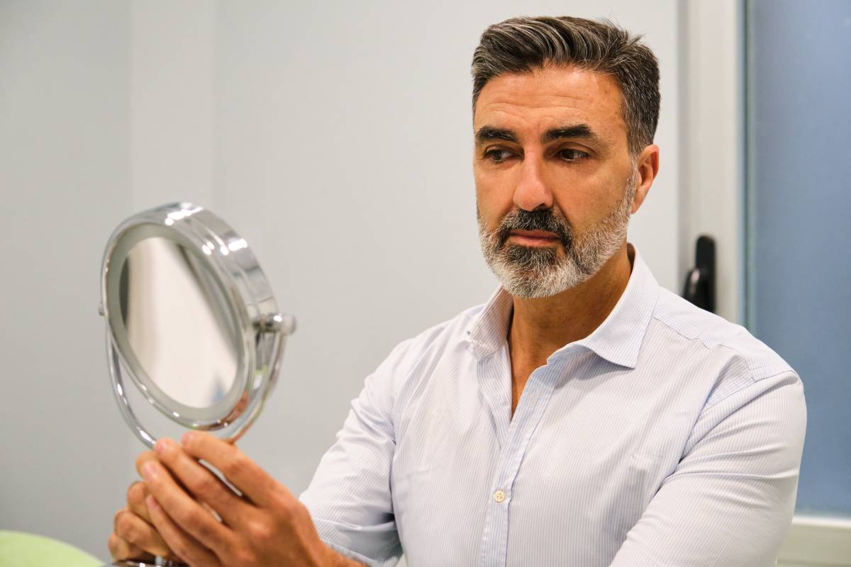 Mature Caucasian man looking into the mirror after a aesthetic treatment.