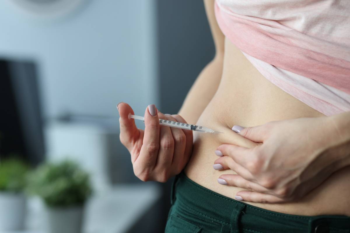 Woman injecting medicine into her stomach.